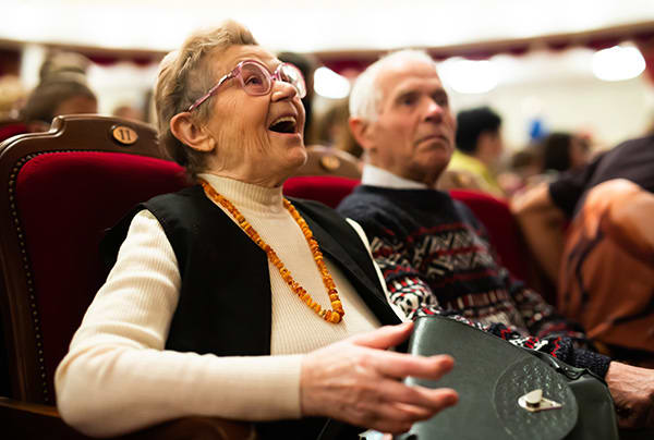 A senior woman expressing excitement while seated in a theater