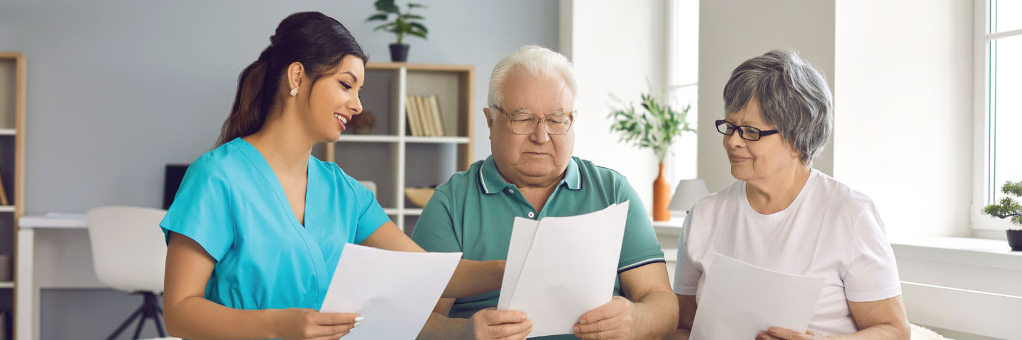 A caregiver reviews a document with a senior couple