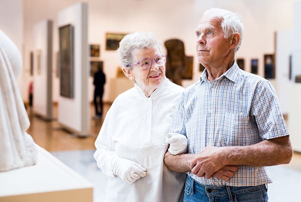 A senior couple walk through an art museum arm-in-arm